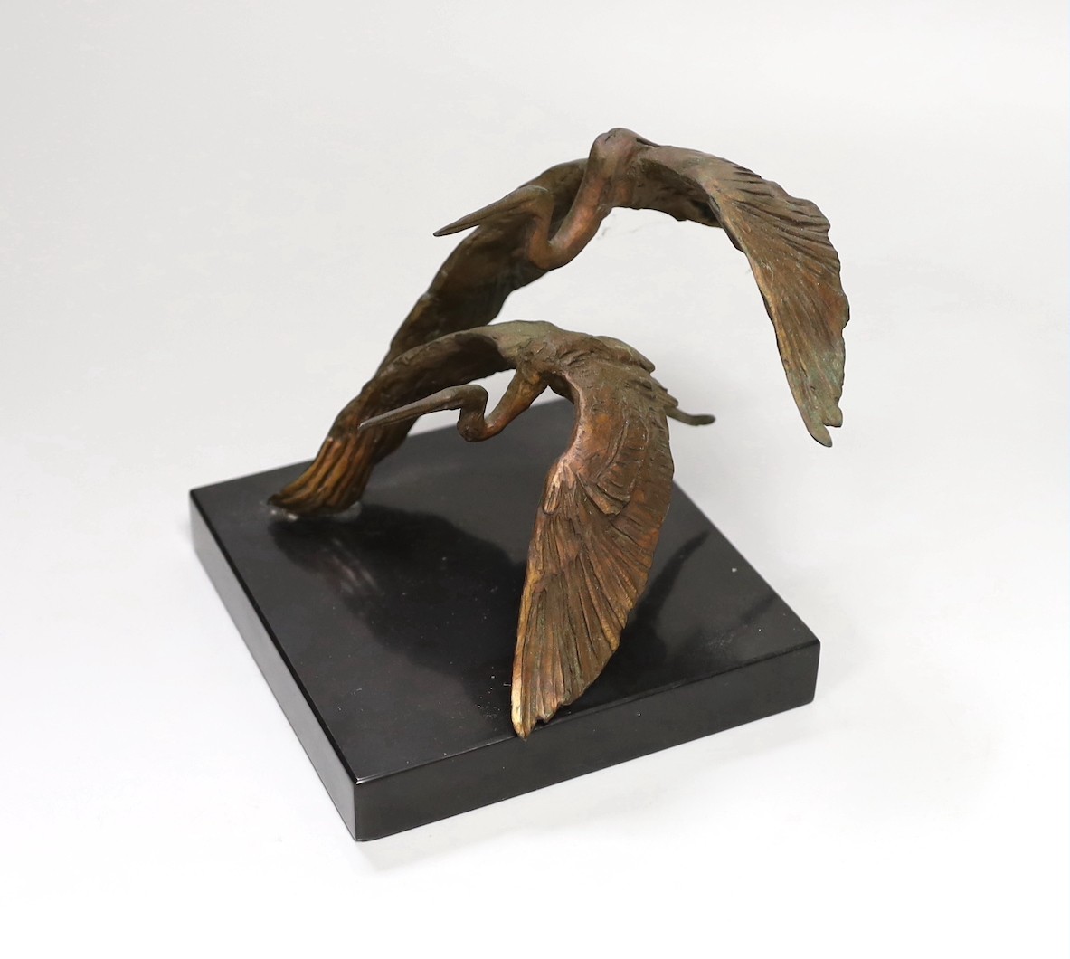 A bronze model of two herons in flight, on slate base 14cm tall